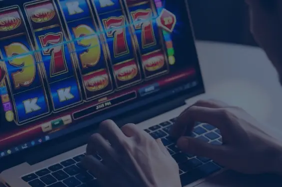 Person playing an online slot machine game on a laptop, featuring colorful symbols and a winning combination.